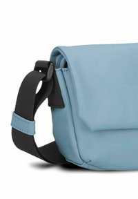 Borsa a tracolla di colore azzurro chiaro con texture liscia, tracolla nera regolabile e chiusura a patta. Include una tasca con zip sul lato.