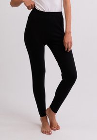 Zwarte leggings met een elastische tailleband, figuurvormend ontwerp en gladde textuur, geschikt voor casual of actieve kleding.
