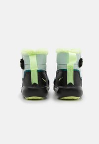 Pair of black and neon green winter boots with fur lining, back pull tabs, and Nike logos, shown from the rear on a white background.