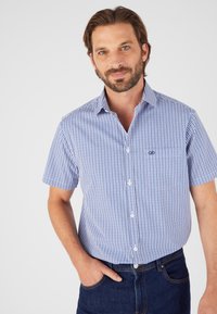 Camicetta a maniche corte, a quadri blu e bianchi, con colletto button-down e taschino frontale, realizzata in un tessuto leggero.