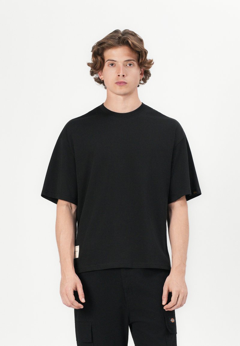 T-shirt noir à manches courtes en tissu doux avec une coupe décontractée, un col rond et une petite étiquette à l'ourlet.