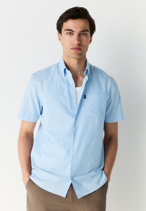 Camicia a maniche corte azzurro chiaro in tessuto liscio, con colletto button-down, taschino frontale e vestibilità comoda.