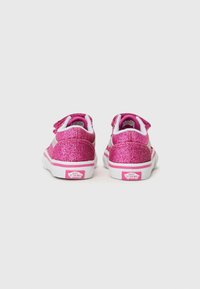 Baskets scintillantes roses avec des accents blancs, sangle à boucle et semelle en caoutchouc blanche. Présente un logo à l'arrière et une surface texturée.