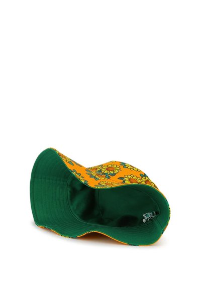 Chapeau seau vert avec un bord et un intérieur à motif floral jaune. Présente une texture douce et un profil flexible pour un port confortable.