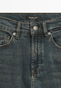 Mörkblå jeans i denim med metallknapp i midjan, fem bälteshällor, framfickor och en Massimo Dutti-etikett sydd på insidan av midjebandet.