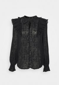 Blouse noire semi-transparente à manches longues avec motif texturé, épaules volantées, devant boutonné et fermeture à nouer au niveau de l'encolure.