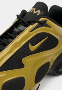 Μαύρο και κίτρινο αθλητικό παπούτσι με υφασμάτινη επιφάνεια, λείες λεπτομέρειες και έντονο λογότυπο Nike στο πλάι. Τα κορδόνια είναι μαύρα με ματ φινίρισμα.
