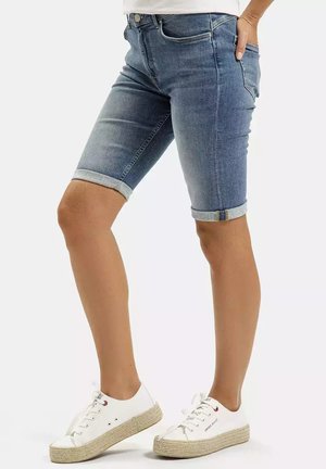 Jasnoniebieskie szorty dżinsowe z podwiniętym dołem, pięcioma kieszeniami oraz zapinane na metalowy guzik, zestawione z białymi espadrylami.