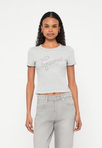 Gray cropped t-shirt with short sleeves, featuring a rhinestone logo design "Guess EST. 1984" across the chest. Soft cotton material.
