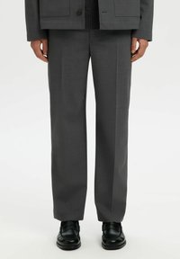 Grau maßgeschneiderte Hose mit geradem Bein-Design, gefertigt aus einem strukturierten Stoff. Verfügt über ein dezentes Webmuster und wird mit schwarzen Schuhen kombiniert.