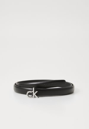Krøllet slank sort læderbælte med sølv styliseret "ck" spænde på en ensartet hvid baggrund.