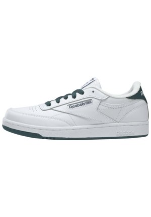 Bílé kožené tenisky s zelenými akcenty, plochá podrážka, kulatá špička a polstrovaný límec. Obsahují logo Reebok na bocích a na jazyku, s minimálními perforacemi.