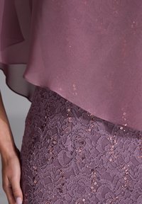Purple lace skirt features intricate floral patterns, adorned with sequins. Flowing chiffon overlay adds soft texture and elegance.