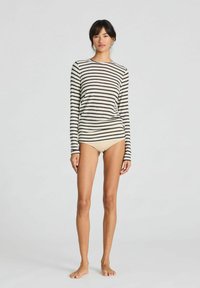 Dugi rukav, prugasti gornji dio u boji off-white i tamno smeđoj, uparen sa svijetlosmeđim donjim rubljem. Mekani materijal s prilagođenim dizajnom i okruglim izrezom.