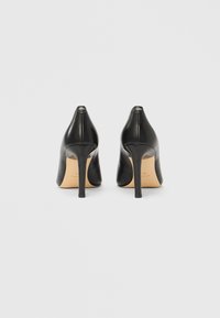 Czarne skórzane szpilki z ostro zakończonym czubkiem i smukłym obcasem typu sztylet. Charakteryzują się gładką fakturą i logo na obcasie.
