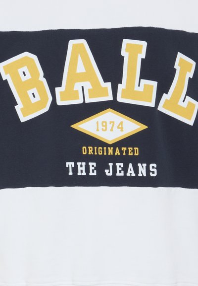 Hanorac bleumarin și alb, cu literă mare galbenă și albă. Textul include "BALL, 1974, ORIGINATING JEANS" cu grafică în formă de diamant.