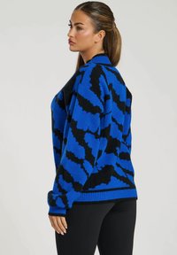 Blå och svart mönstrad oversize-tröja med rund halsringning, stickad textur, sänkta axlar samt ribbade ärmslut och nederkant.