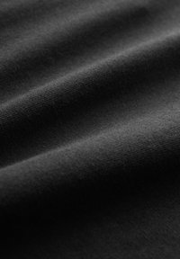 Black fabric with a soft, matte texture, featuring smooth, slightly wrinkled folds, showcasing its flexible and lightweight design.