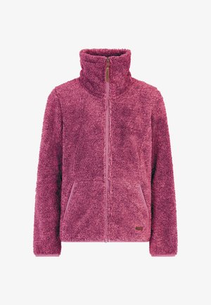 Glückliches Mädchen in einem lila Fleecejacke mit Reißverschluss, Leoprint-Hose und schwarzen Stiefeln, stehend vor einem weißen Hintergrund.