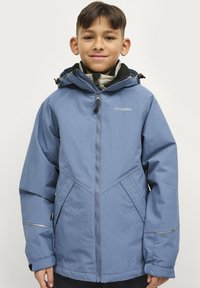 Blauwe waterdichte jas met capuchon, voorzien van een ritssluiting aan de voorkant, schuine zakken en reflecterende accenten. Gladde textuur met een slank ontwerp.