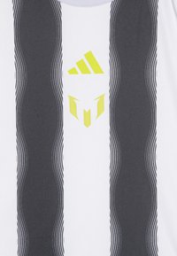 Das weiße Sportshirt verfügt über auffällige vertikale schwarze Streifen und wellenförmige graue Akzente. Hervorgehobene Logos in leuchtendem Gelb sind in der Mitte platziert.