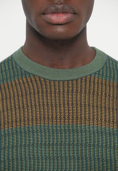 Sweter dziergany z pionowymi paskami w kolorze zielonym, brązowym i żółtym. Okrągły dekolt wykończony ściągaczem oraz różnorodna faktura na całej powierzchni.
