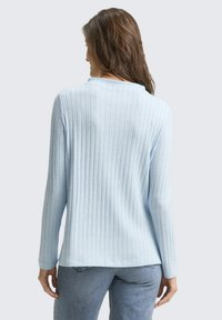 Helles blaues, geripptes Sweatshirt mit langen Ärmeln und rundem Ausschnitt. Der Stoff wirkt weich mit einer feinen Textur.