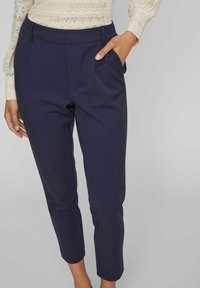 Mörkblå skräddarsydda byxor med slim fit, sidofickor och en slät tygfinish. Har en platt front och design i ankellängd.
