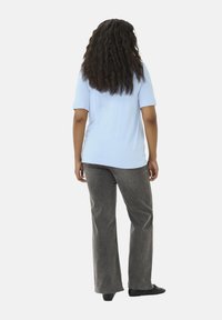 Lichtblauw kortemouzen top en grijze wijde broek. De top heeft een gladde textuur; de broek is gemaakt van een gestructureerde stof met een losse pasvorm.