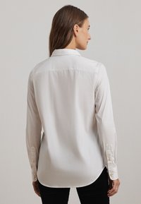 Witte button-up shirt met een klassieke kraag, lange mouwen en een afgeronde zoom. Beschikt over een gladde textuur en manchetten met knoopdetail.