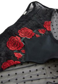 Sort gennemsigtig lingeri lavet af stof med røde broderede roser og grønne blade, kombineret med solidt sort stof og detaljer i polka dot mesh.