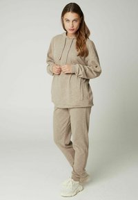 Beige hoodie en sweatpants set in zachte stof, met een trekkoordcapuchon, zijzakken en een losse pasvorm. Accentueert met een lichte textuur.