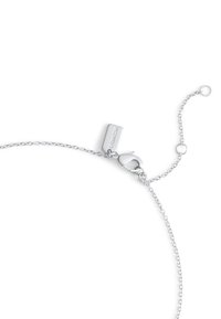 Bracelet en chaîne argentée avec un fermoir à homard et une étiquette rectangulaire gravée "COACH". Présente un design délicat et entrelacé.
