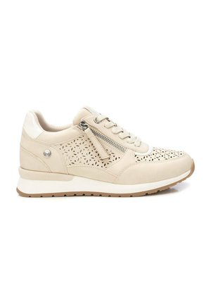 Zapatilla beige con cierre de cordones, cremallera lateral, patrón floral perforado, cuello acolchado y suela blanca con dibujo marrón.