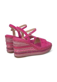 Sandalias de cuña de ante rosa con tiras entrecruzadas y una suela de estilo espadrille trenzada, con acentos decorativos a lo largo de la base.