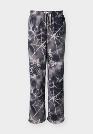Pantalon de survêtement noir et gris avec cordon blanc, présentant un motif intégral de toile d'araignée et de flammes.