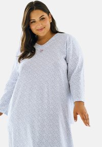 Jasnoniebieska koszula nocna z długimi rękawami, z kwiatowym wzorem, dekoltem w kształcie litery V oraz delikatnymi zdobieniami na piersi. Wykonana z miękkiego materiału.