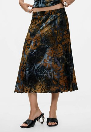 Falda de longitud media con patrones florales de terciopelo negro y marrón combinada con zapatos de tacón abiertos negros con tacones metálicos esculpidos.
