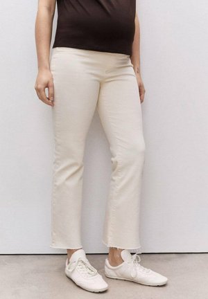 Light beige straight-leg jeans with a raw hem, paired with white sneakers. The fabric appears smooth with minimal stretch.
