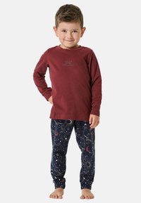 Rotes Langarmhemd mit gedrucktem Design, kombiniert mit navyfarbenen Schlafanzug, der ein himmlisches Muster aus Sternen und Planeten aufweist. Weicher Stoff, lässige Passform.