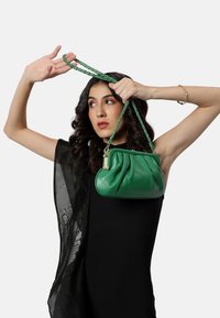 Borsa a tracolla verde in pelle con design morbido, tracolla intrecciata verde, dettagli in metallo dorato e superficie liscia.
