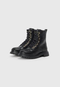 Bottines noires avec une surface texturée, œillets dorés et lacets noirs. Dotées d'une semelle en caoutchouc solide et d'un talon légèrement surélevé.