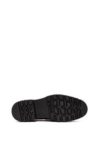 Suela de goma negra con un patrón de relieve profundo, que presenta texturas en zigzag y circulares para tracción y agarre. Diseño de tacón plano y punta redondeada.