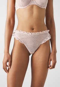 Helle rosa Spitzenunterwäsche mit kleinen Punkten, versehen mit Rüschendetails entlang des Taillenbundes. Hergestellt aus transparentem Material mit weicher Textur.
