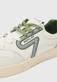Weiße Leder-Sneaker mit grünen und grauen Akzenten, ausgestattet mit strukturierten Einsätzen, runden Schnürsenkeln und dem 'REPLAY'-Logo an der Seite.