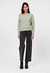 Lys grønn avskåret genser med løs passform, kombinert med høytlivede sorte vide jeans og svarte ankelstøvler.