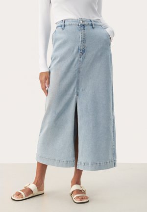 Jeansrock in Hellblau mit einem Schlitz vorne, hoher Taille, Seitentaschen und geradem Schnitt. Kombiniert mit weißen Sandalen mit einer dekorativen Schnalle.