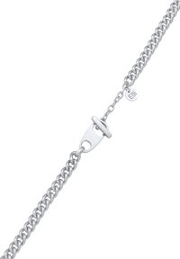 Bracelet en cha�îne argentée avec des maillons entrelacés, un fermoir à bascule et une petite étiquette gravée. Texture lisse avec une finition polie.