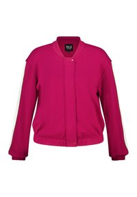 Veste bomber fuchsia avec des rayures blanches sur le côté, poches zippées, poignets côtelés et col rond. Fabriquée en tissu lisse et léger.