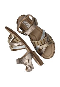 Metalen gouden en zilveren sandaal met kruislingse banden en een gestructureerde afwerking. Bevat een platte zool en een verstelbare enkelband.